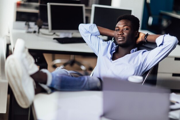 Hombre de negocios africano joven que se relaja en su oficina. Tiempo para descansar después de trabajar.