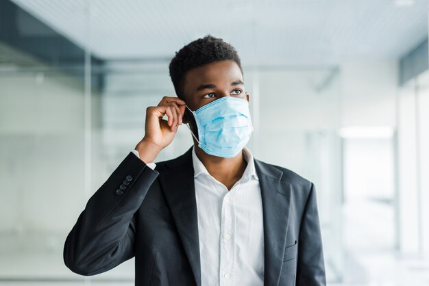 Hombre de negocios africano con una protección bucal para evitar enfermarse en el trabajo en la oficina