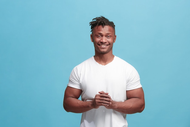 El hombre de negocios afroamericano feliz de pie y sonriendo sobre fondo azul.