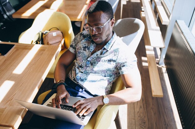 Hombre de negocios afroamericano que trabaja con la computadora portátil en un café