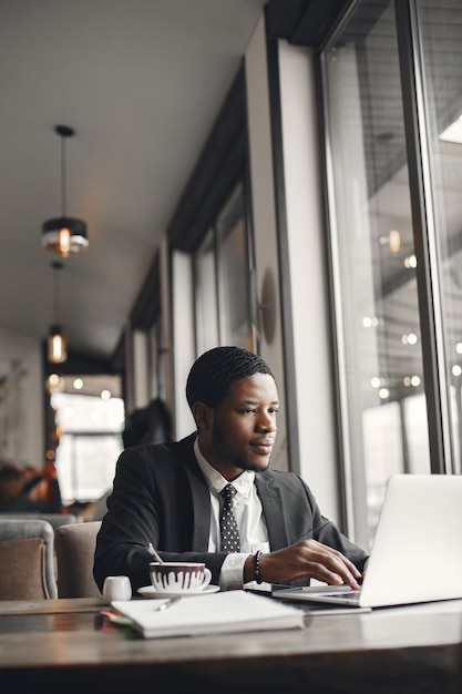 Hombre de negocios afroamericano usando una computadora portátil en un café.