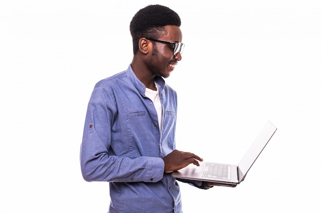 Hombre de negocios afroamericano usando una computadora portátil y posando aislado sobre pared blanca