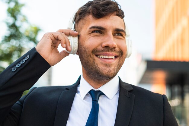 Hombre de negocios al aire libre escuchando música feliz