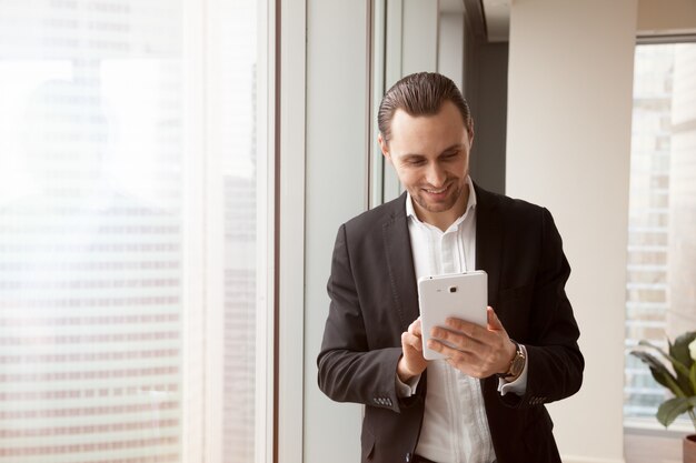 Hombre de negocios alegre que usa la aplicación móvil en la tableta