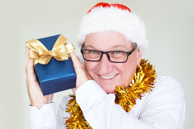Hombre de negocios alegre en el sombrero de Santa que muestra el presente