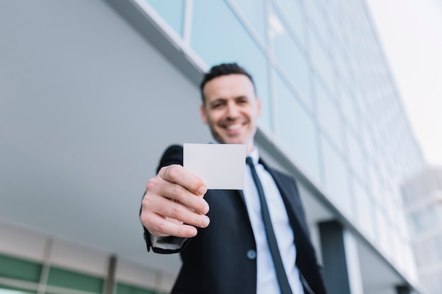 Hombre de negocios amable enseñando tarjeta de visita