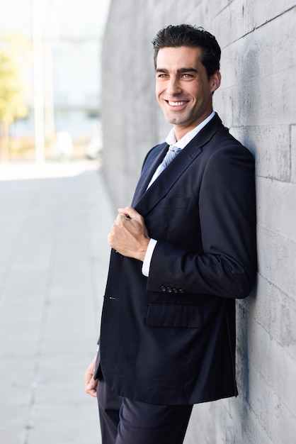 Hombre de negocios apoyado en una pared sonriendo