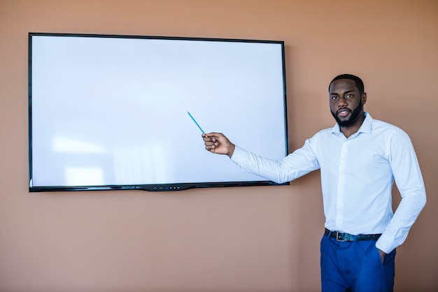 Foto gratuita hombre de negocios apuntando a tablero blanco