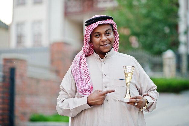 Hombre de negocios árabe del Medio Oriente posó en la calle con una copa de oro en las manos