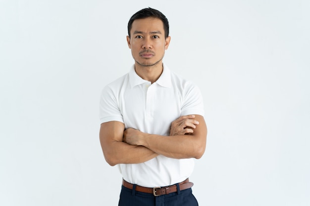 Hombre de negocios asiático serio en la camiseta blanca que mira la cámara