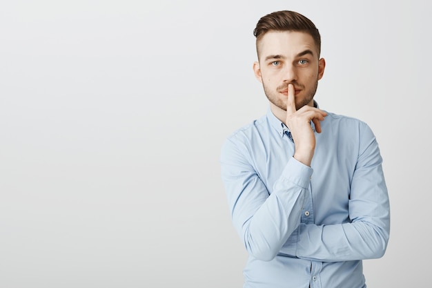 Hombre de negocios de aspecto serio dice shh, haciendo un gesto de silencio, necesita silencio para pensar