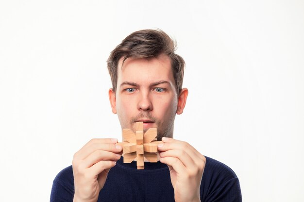 Hombre de negocios atractivo de 25 años mirando confundido en rompecabezas de madera.