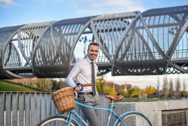 Hombre de negocios con bicicleta vintage junto al río.