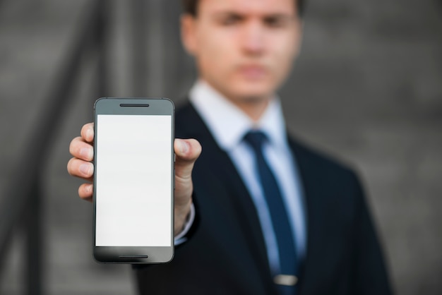 Foto gratuita hombre de negocios borroso enseñando smartphone