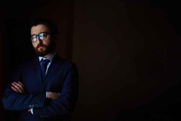 Foto gratuita hombre de negocios con los brazos cruzados en la oscuridad