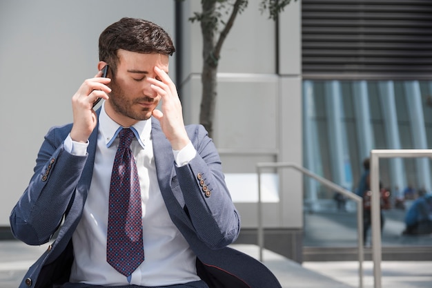Hombre de negocios cansado hablando en teléfono inteligente