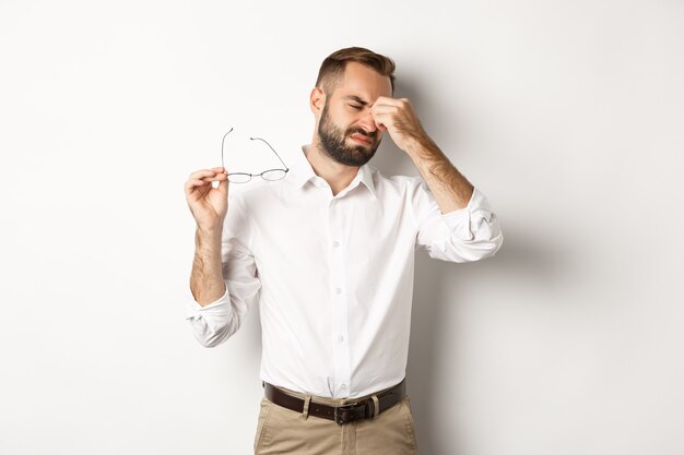 Hombre de negocios cansado quitarse las gafas y frotarse los ojos, de pie agotado