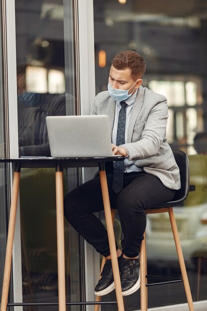 Hombre de negocios en una ciudad. Persona con máscara. Chico con laptop.