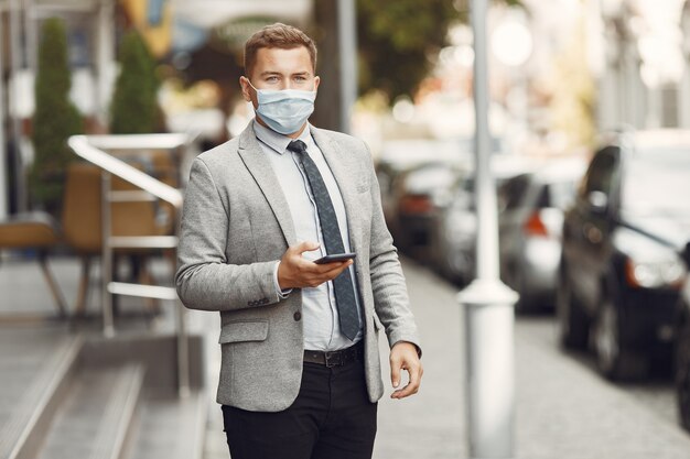 Hombre de negocios en una ciudad. Persona con máscara. Chico con teléfono.