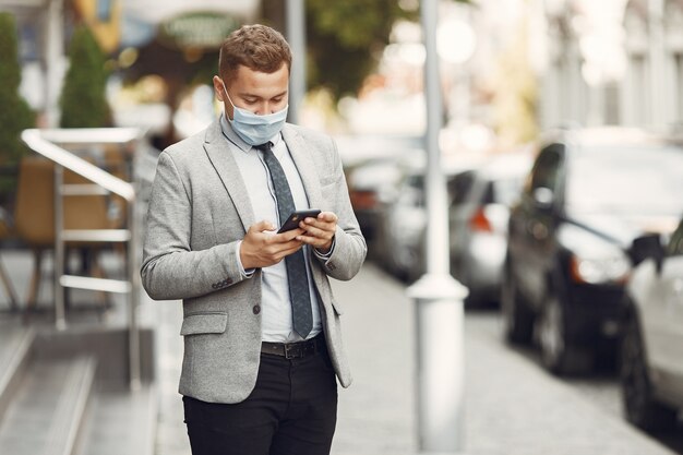 Hombre de negocios en una ciudad. Persona con máscara. Chico con teléfono.