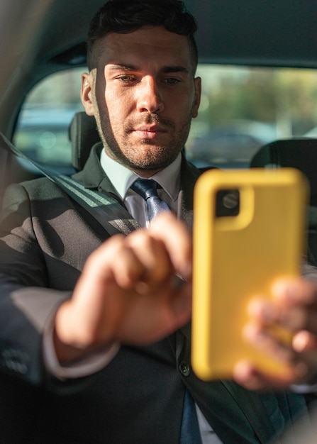 Foto gratuita hombre de negocios en el coche mediante teléfono móvil