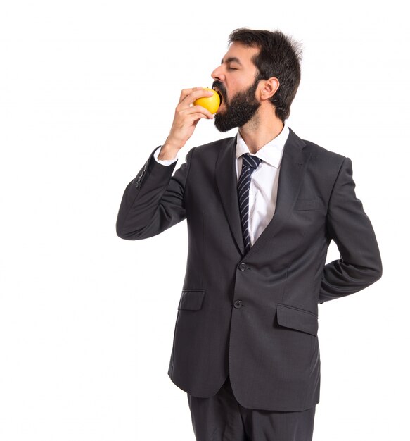 Hombre de negocios comiendo una manzana sobre blanco