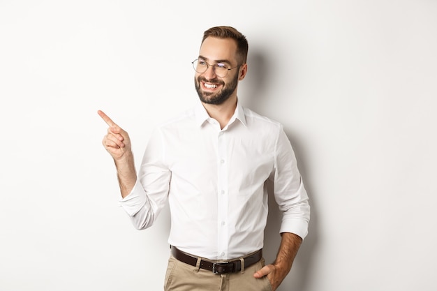 Hombre de negocios confiado que parece satisfecho y que señala el dedo a la izquierda