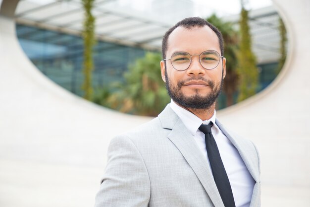 Hombre de negocios confidente positivo que presenta afuera