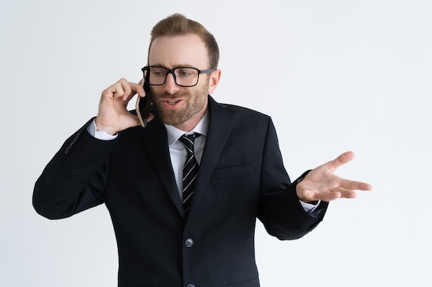 Hombre de negocios confuso en chaqueta negra que habla en el teléfono