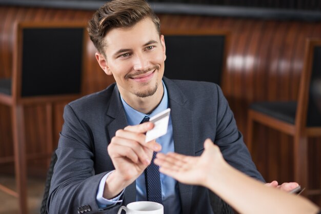 El hombre de negocios de contenido Donante de la tarjeta de camarero en el Café