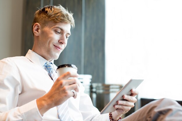 Hombre de negocios contento con la taza y la tableta