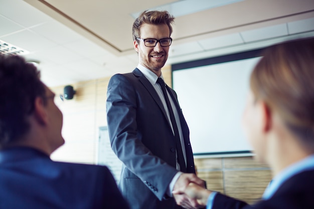 Hombre de negocios dándose la mano con su compañera de trabajo