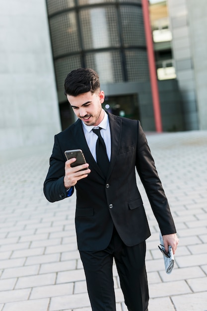 Foto gratuita hombre de negocios delante del edificio de la oficina usado su móvil