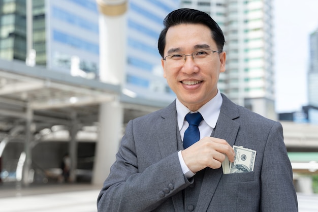 Hombre de negocios con dinero billetes de un dólar en la mano en el distrito de negocios