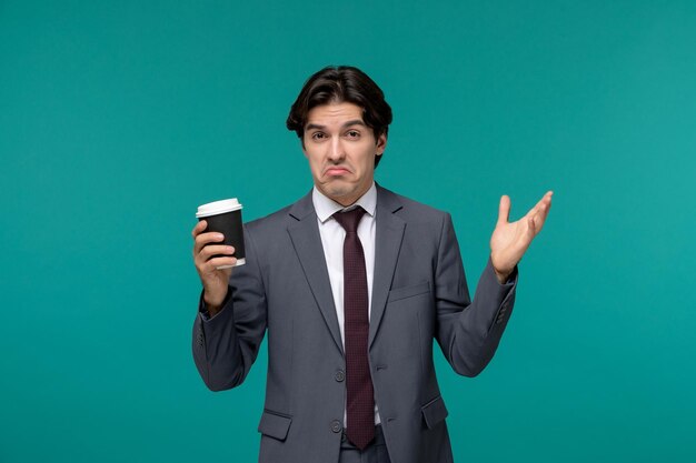 Hombre de negocios elegante lindo guapo en traje de oficina gris y corbata agitando las manos con vaso de papel