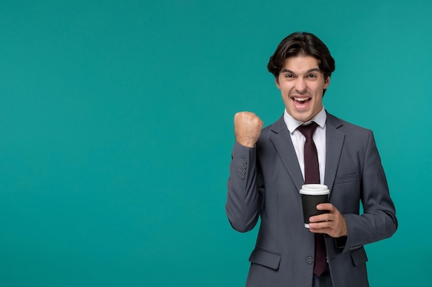 Hombre de negocios elegante lindo guapo en traje de oficina gris y corbata emocionado con la taza de café