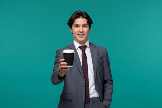 Hombre de negocios elegante lindo guapo en traje de oficina gris y corbata mostrando taza de café