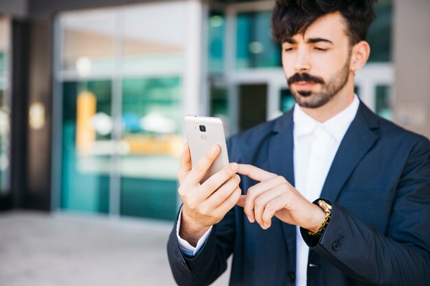 Hombre de negocios elegante mirando a smartphone