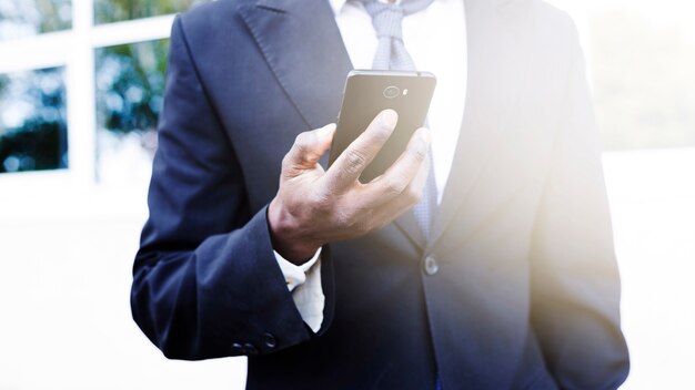 Hombre de negocios elegante mirando a smartphone