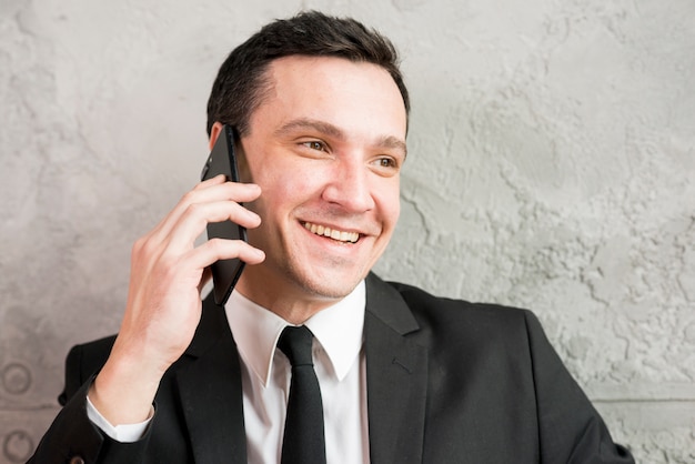 Hombre de negocios elegante sonriente que habla en el teléfono