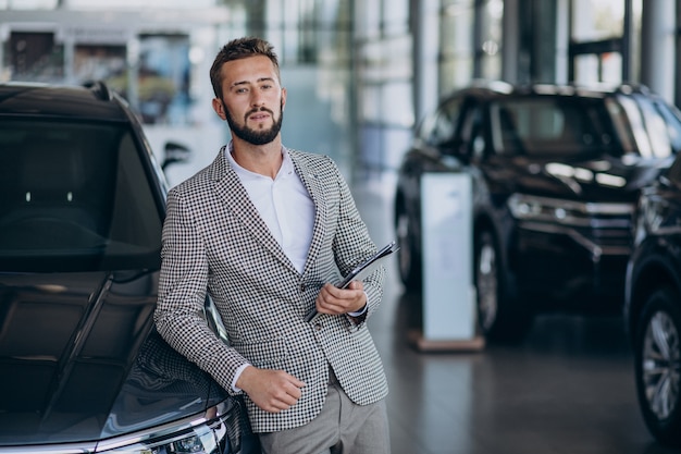 Hombre de negocios eligiendo un coche en una sala de exposición de coches