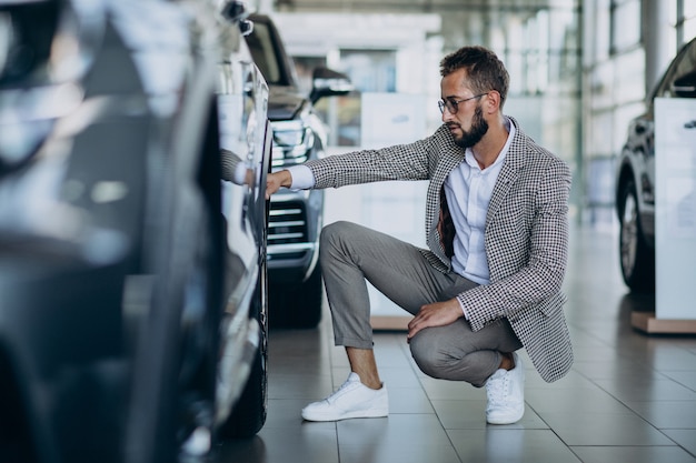 Hombre de negocios eligiendo un coche en una sala de exposición de coches