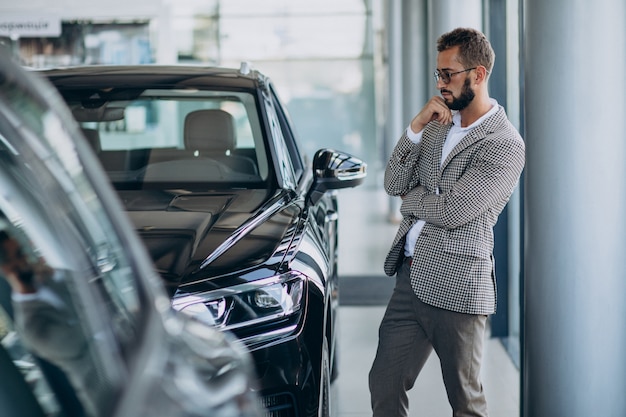 Hombre de negocios eligiendo un coche en una sala de exposición de coches