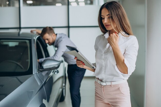 Hombre de negocios eligiendo un coche con una vendedora en el salón del automóvil