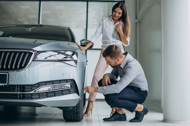 Hombre de negocios eligiendo un coche con una vendedora en el salón del automóvil