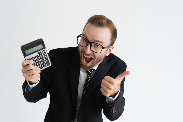 Hombre de negocios emocionado que muestra la pantalla y el pulgar de la calculadora. Concepto de cálculo