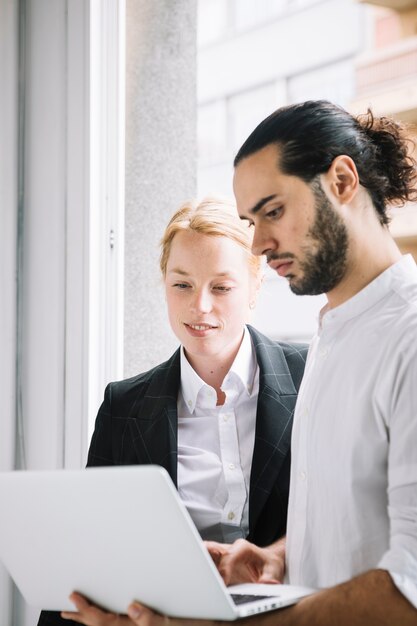 Hombre de negocios y empresaria jovenes que usa el ordenador portátil