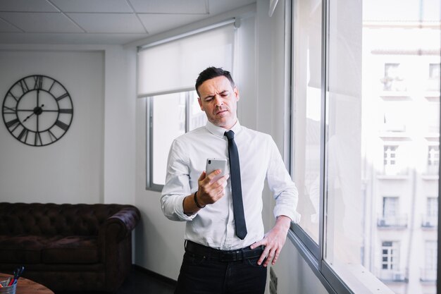 Hombre de negocios enfadado mirando a smartphone