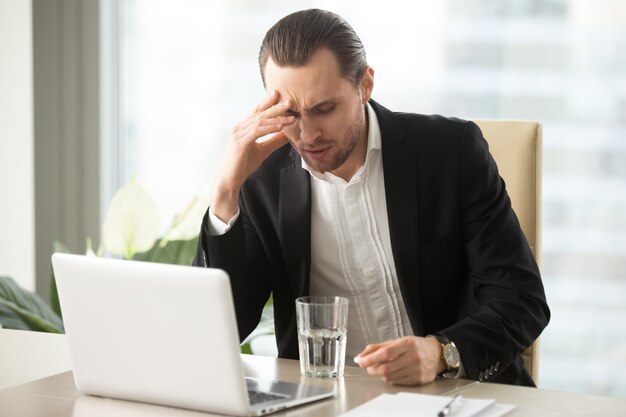 Hombre de negocios enfermo que tiene dolor de cabeza severo