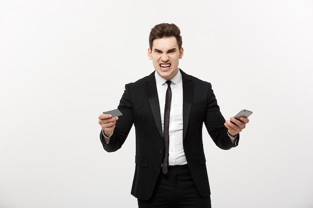 Hombre de negocios enojado con tarjeta de crédito y teléfono móvil. Enloquezca mientras compra en línea o tiene un problema comercial.